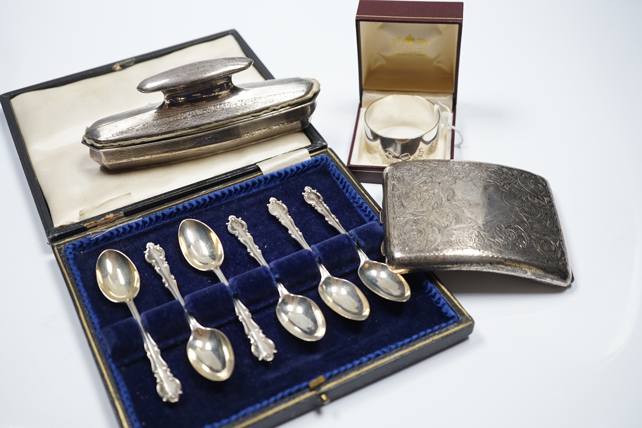 A George V engraved silver mounted nail buffer with cover, Birmingham, 1928, 14.9cm, together with a silver cigarette case, a silver napkin ring and a cased set of six silver teaspoons.